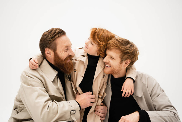 redhead kid embracing happy dad and grandfather smiling at each other isolated on grey - Zdjęcie, obraz