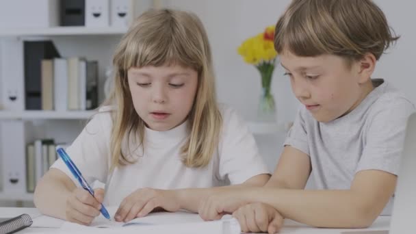 Boy of 9 years old helps his younger sister to make her homework. High quality 4k footage - Filmagem, Vídeo