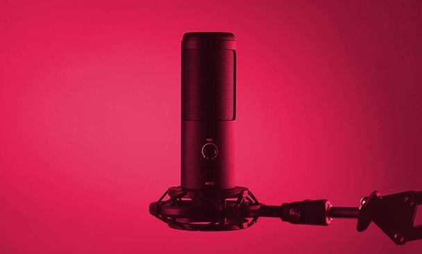 Студийный конденсатор микрофон изолирован на темном фоне. Изображение тонировано в Viva Magenta, цвет 2023 года. - Фото, изображение
