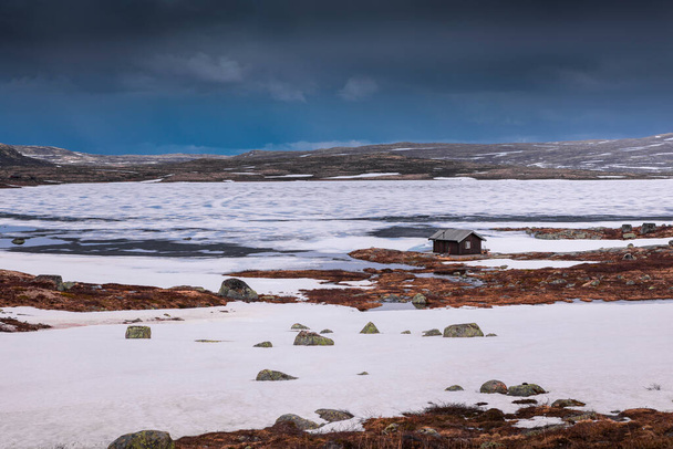 На берегу замерзшего озера в ландшафте национального парка Хардангервидда в Норвегии снег и лед на земле - Фото, изображение