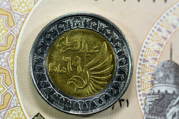 エジプトの反対側1 LE EGPエジプト銀行券上の1エジプトポンド硬貨、飛んで鷹とエジプト警察の日を記念してアラビア語(警察日69年)の翻訳 - 写真・画像