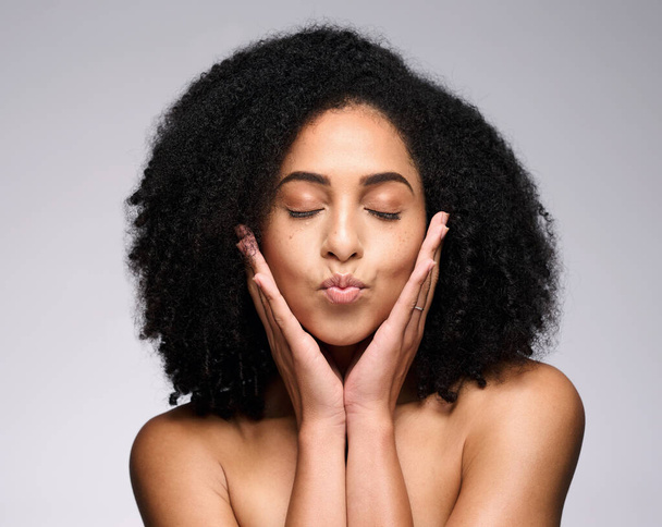 Face kiss, beauty skincare and black woman with eyes closed in studio isolated on a gray background. Makeup, natural cosmetics and young female model pouting lips satisfied with spa facial treatment - Photo, Image
