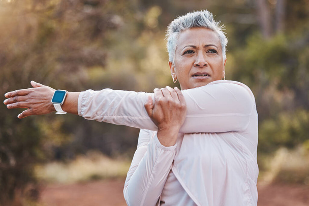 Exercise, stretching and senior woman outdoor in nature for running, cardio fitness and a workout with a smartwatch. Elderly female in a forest for cardio training for a healthy lifestyle and body. - Foto, imagen