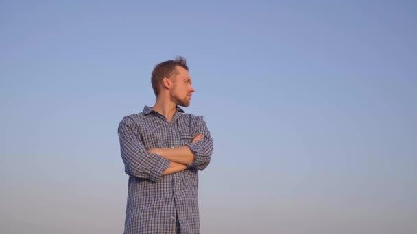 Attractive bearded caucasian male standing outdoor wearing sleep wear looking at side. Relaxing morning or chill out concept. Clear blue sky at background. High quality 4k video footage - Imágenes, Vídeo