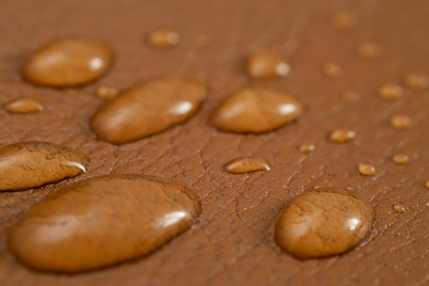 Кругла вода падає на текстуру коричневої шкіри, вид збоку, м'який макрос фокусу
 - Фото, зображення