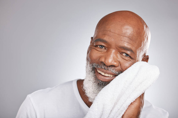 Skincare, portrait or old man with a face towel in studio with marketing or mock up space for beauty. Happy smile, glowing skin or healthy senior black man grooming with facial cosmetics or product. - Foto, Bild