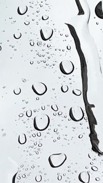 Настоящий дождь падает на стекло и создает маленькие капли воды. Качественные кадры - Кадры, видео