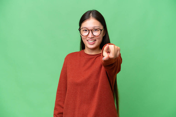 Young Asian woman over isolated background looking far away with hand to look something - Foto, afbeelding