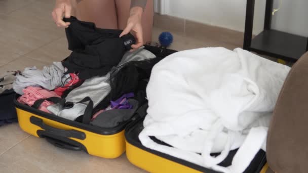 Matkustava nainen vetää asioita keltaisesta matkalaukusta loman jälkeen.. - Materiaali, video