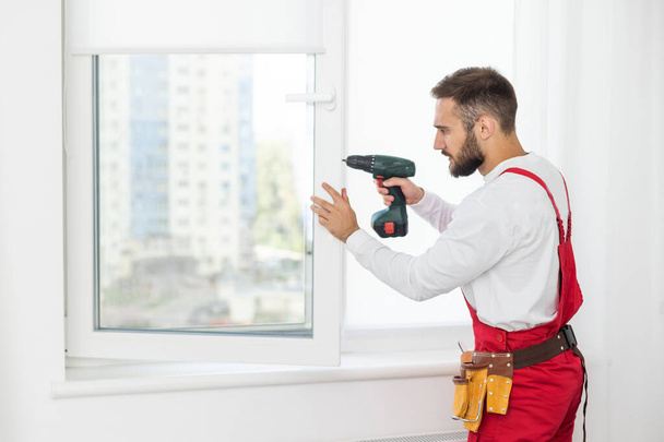 service man installing window with screwdriver. - Photo, Image