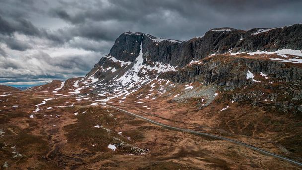 Landscape with road and mountain ridge in Jotunheimen National Park in Norway from above, dramatic dark cloudy sky - Fotó, kép