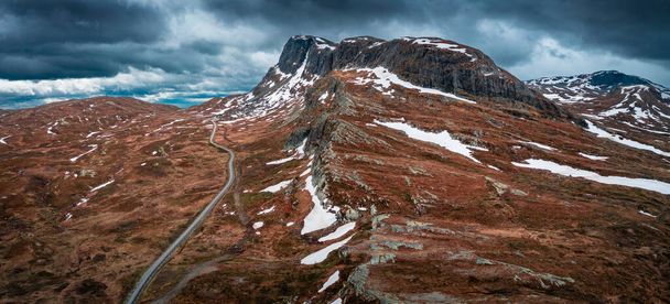 Landscape with road and mountain ridge in Jotunheimen National Park in Norway from above, dramatic dark cloudy sky - Foto, Imagem