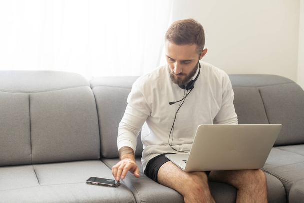 Młody człowiek freelancer za pomocą laptopa studiuje online pracy z domu, szczęśliwy casual facet wpisując na notatniku - Zdjęcie, obraz