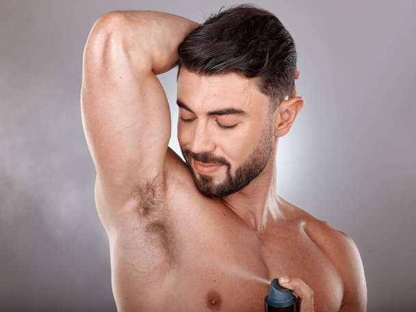 Spray deodorant and man happy with product for armpit hygiene, grooming and cosmetic campaign. Body care, wellness and skincare model with healthy skin glow in gray studio background - Foto, Bild