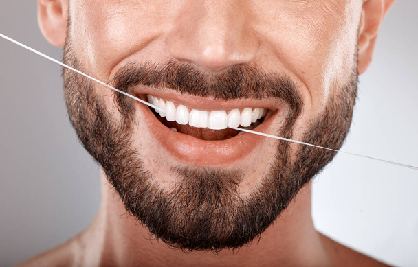 Dentist, floss and mouth of man with smile on gray background in studio for wellness, healthcare and hygiene. Dental care, grooming and zoom of male model for dentistry, cleaning and flossing teeth. - Zdjęcie, obraz