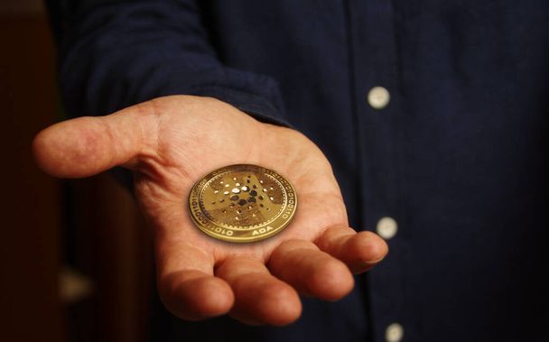 Cardano ADA cryptogeld gouden munt in de hand abstract concept - Foto, afbeelding