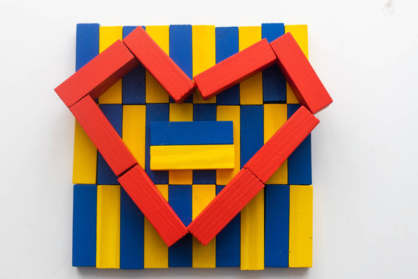 Πλαστικές κίτρινες-μπλε λεπτομέρειες του παιδικού σχεδιαστή σε σχήμα καρδιάς. Παιδικό εκπαιδευτικό παιχνίδι, κορυφαία άποψη. Σημαία Ουκρανίας. - Φωτογραφία, εικόνα