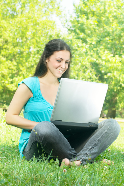 Щаслива молода жінка використовує ноутбук на відкритому повітрі
 - Фото, зображення