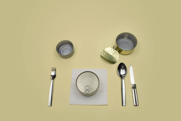 Silverware knife fork spoon cans empty closed on blue, cutlery.Nothing for dinner. What are you going to put on your plate can dish?On yellow background. Nice copy space. - Foto, Imagem