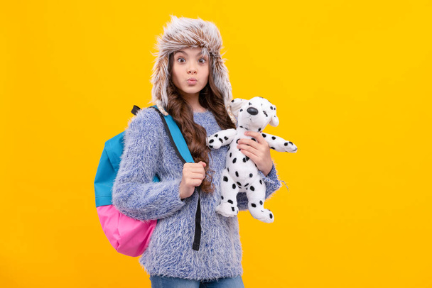 funny kid long hair in hat with schoolbag and toy on yellow background, back to school. - Foto, immagini