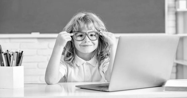 allegro ragazzo in occhiali studio online a scuola classrrom con computer portatile, settembre. - Foto, immagini