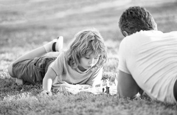 família feliz de pai e filho menino jogando xadrez na grama verde no parque ao ar livre, estratégico. - Foto, Imagem