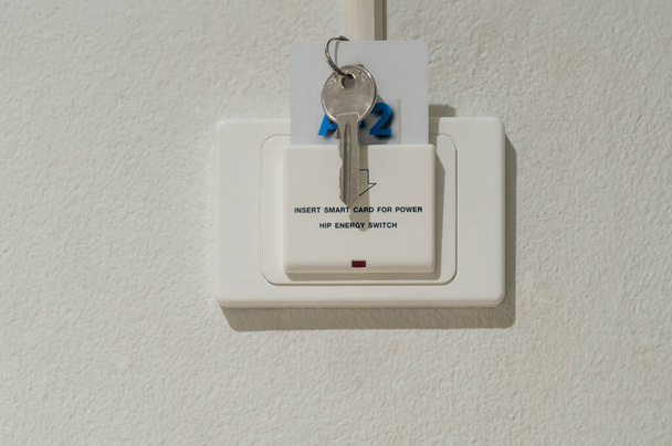 Smart card with key is inserted into white socket with text reading Insert smart card for power installed on white wall in luxurious hotel or resort room. - Zdjęcie, obraz
