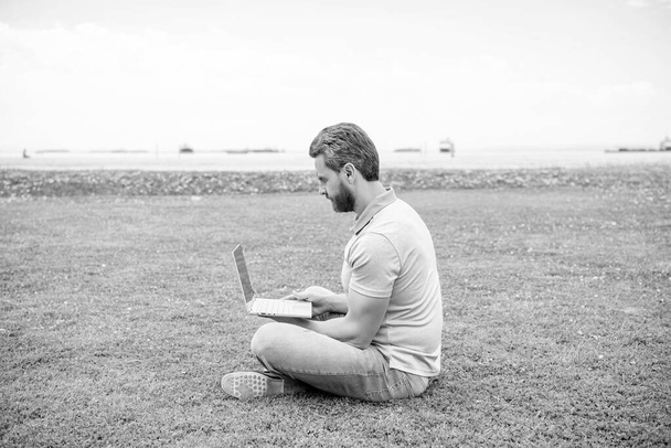 бизнесмен использует ноутбук для ведения блога. социальная сеть и блог. современная деловая компьютерная связь. бородатый парень проверяет почту. Свободный человек ведет блог в Интернете, сидит на траве. написание онлайн. - Фото, изображение