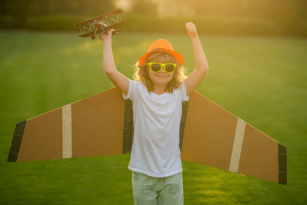Child freedom and carefree. Happy child playing outdoor. Kid having fun with toy paper wings - Fotó, kép