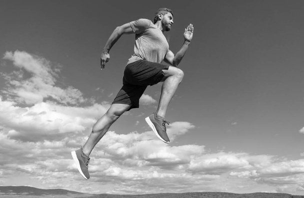 hombre musculoso corriendo en ropa deportiva al aire libre en el fondo del cielo, desafío. - Foto, imagen