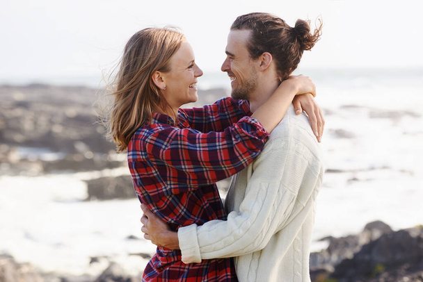 Только мы вдвоем... любящая молодая пара, обнимающаяся, стоя на пляже - Фото, изображение