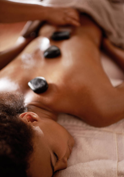 Sticks and stones will heal these bones...a young woman enjoying hot stone therapy at a spa - Foto, afbeelding