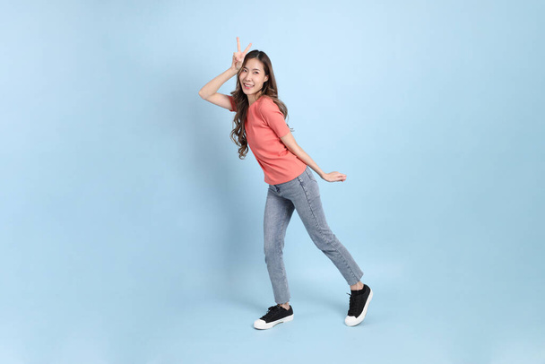 The young adult Asian woman with casual clothes with jeans standing on the blue background. - Foto, imagen