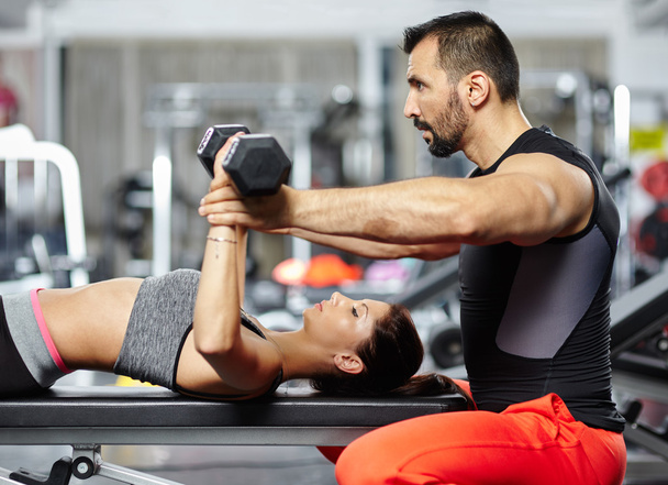 Personal trainer assisting young woman - 写真・画像