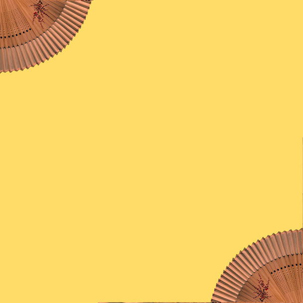 Elegant wooden two fans with fine patterns on an yellow background.. Flat lay concept. - Foto, imagen