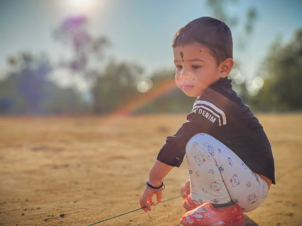 Cute little baby boy playing with rope  in a park and smiling. Child crawling in a public park and looking up with happy face. View from bottom. Copy space - Foto, Imagem