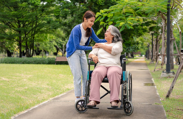 アジア人介護者や看護師が車椅子で患者の世話をする。介護者の介護による幸せな退職の概念と貯蓄と高齢者健康保険、幸せな家族 - 写真・画像