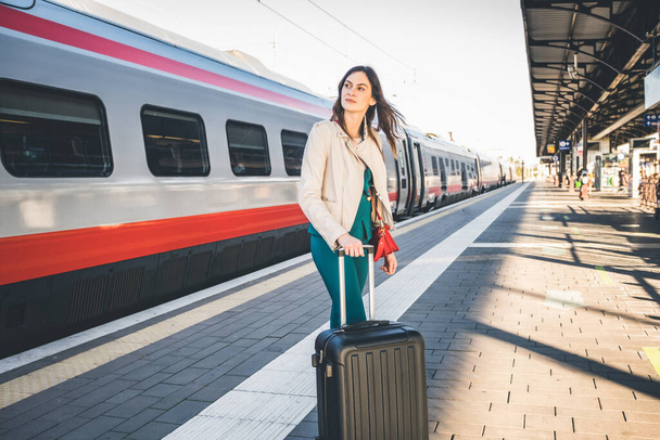 Portrait d'une femme d'affaires qui se promène dans une gare ou un aéroport pour se rendre à la porte d'embarquement avec bagages à main - Photo, image