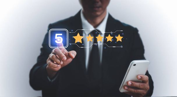 A man points with his finger and selects a number five and a five star to display on the virtual screen. The user experience or customer satisfaction survey, poll, or questionnaire. - Photo, Image