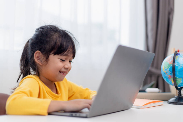 Первый день в школе. Азиатская девочка с помощью ноутбука, изучает через систему электронного обучения онлайн. - Фото, изображение