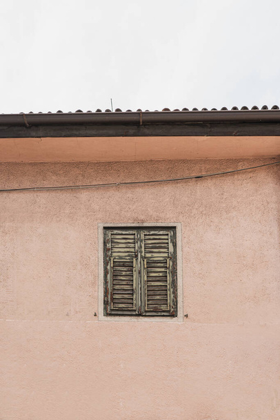 Antique wooden window with shutters on neutral pink wall. Historic architecture in Italy. Aesthetic summer vacation travel concept - Foto, Imagem