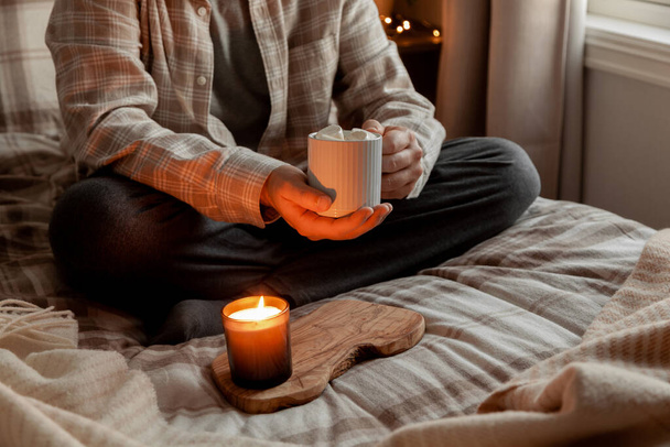 家でリラックスした白人男性照明ろうそくベッドでコーヒーを飲み - 写真・画像