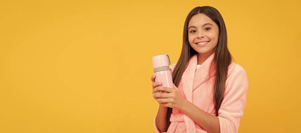 gelukkig tiener meisje in huis badstof badjas met thermosfles, ochtend. Horizontale poster van geïsoleerd kindergezicht, banner header, kopieerruimte - Foto, afbeelding