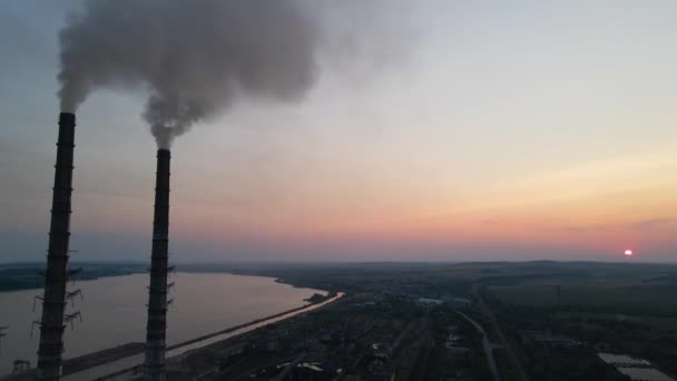 Luchtfoto van hoge pijpen van kolencentrales met zwarte rook die bij zonsondergang naar boven beweegt en vervuilende atmosfeer. Productie van elektrische energie met fossiele brandstoffen. - Video