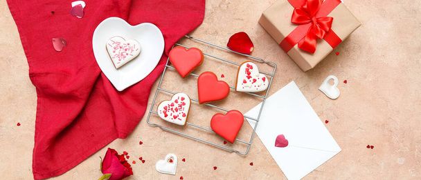 Σύνθεση με νόστιμα μπισκότα σε σχήμα καρδιάς, δώρο και φάκελο σε φόντο grunge. Γιορτή του Αγίου Βαλεντίνου - Φωτογραφία, εικόνα
