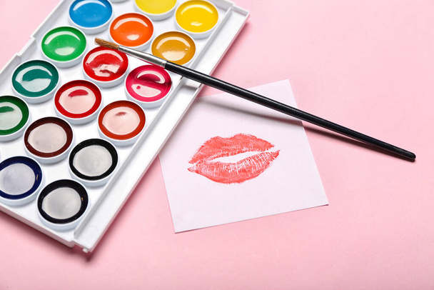 Paperi huulipuna suudella merkki, harja ja maalit vaaleanpunainen tausta - Valokuva, kuva
