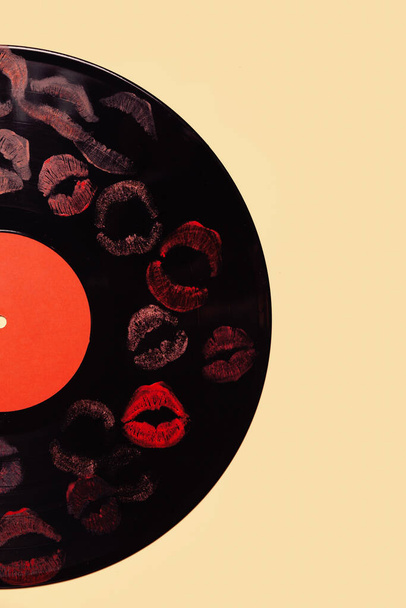 Vinyl record with lipstick kiss marks on yellow background - Zdjęcie, obraz