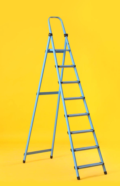 Maintenance ladder on yellow background - Foto, afbeelding