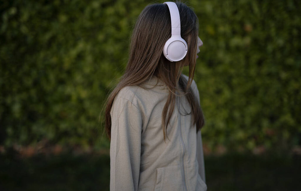 photo in dark tone of a girl listening to music outdoors - Foto, imagen