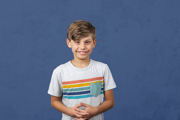 a cute autistic elementary school boy on a blue background with copy space. - Fotó, kép